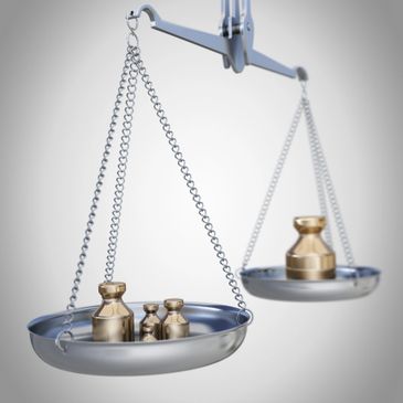 Metal weights on a balance scale with one side heavier.