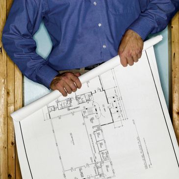 Person holding a rolled architectural blueprint against a wooden frame.