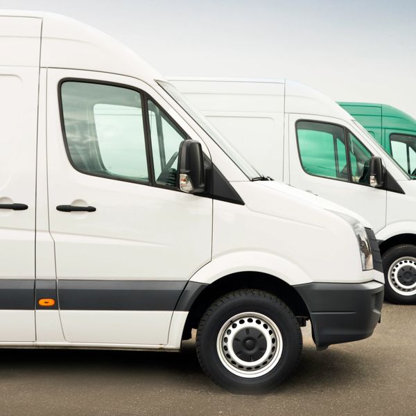 Line of white and green delivery vans parked in a row.