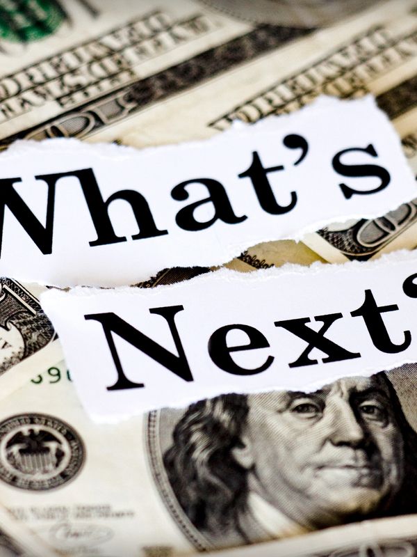 Torn paper with "What's Next" over US dollar bills.