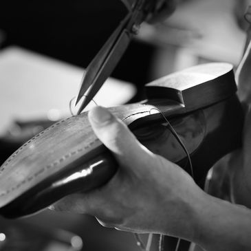 A cobbler hand-stitching the sole of a leather shoe.