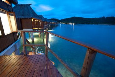 Wooden deck overlooking water bungalows at dusk.