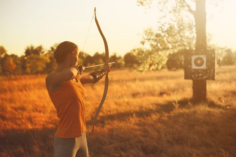 Female archer in the field at sunset