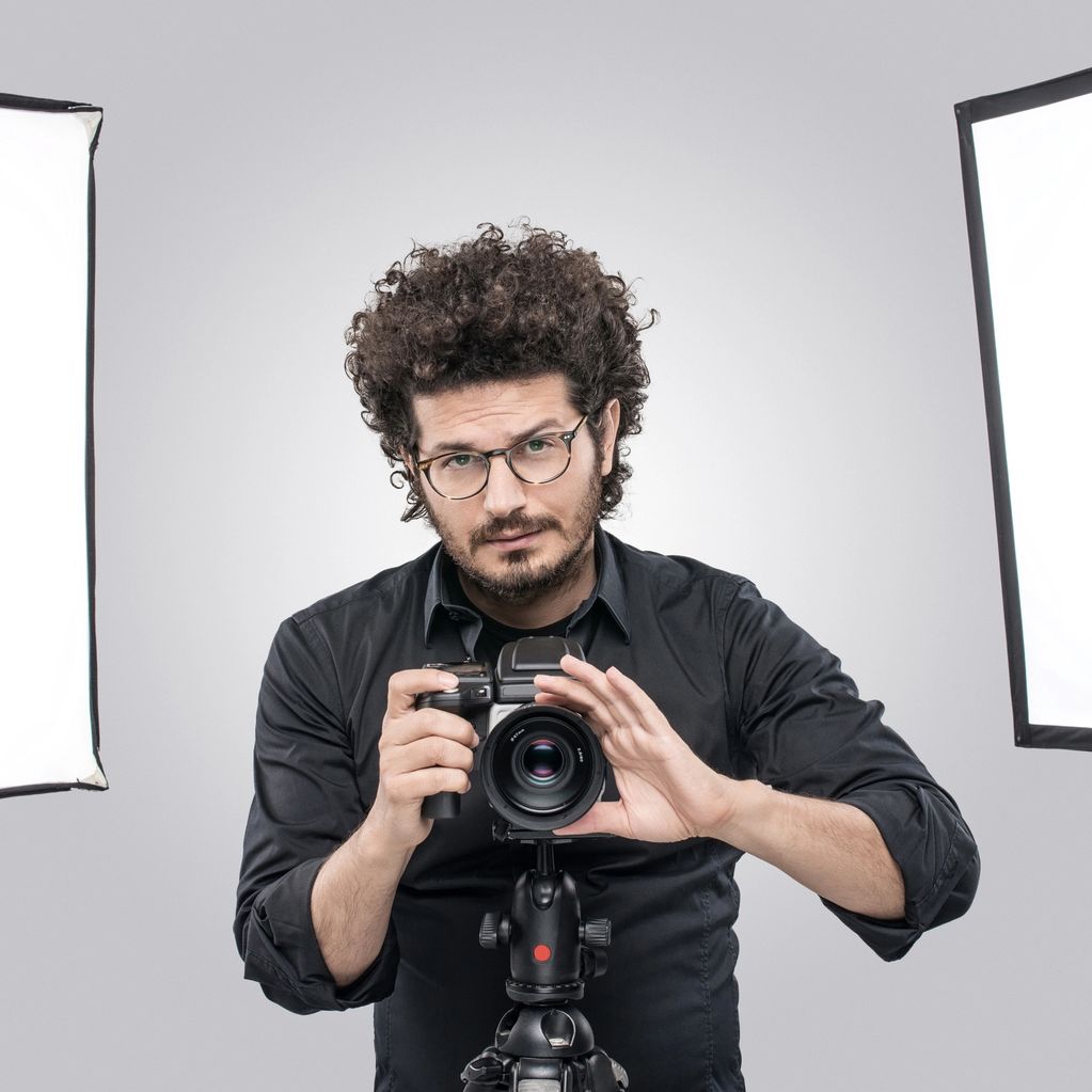 Photographer adjusting camera in a studio with professional lighting.