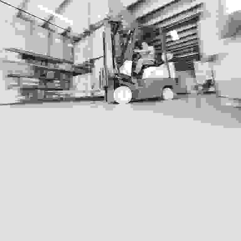 Worker operating a forklift in a busy warehouse.