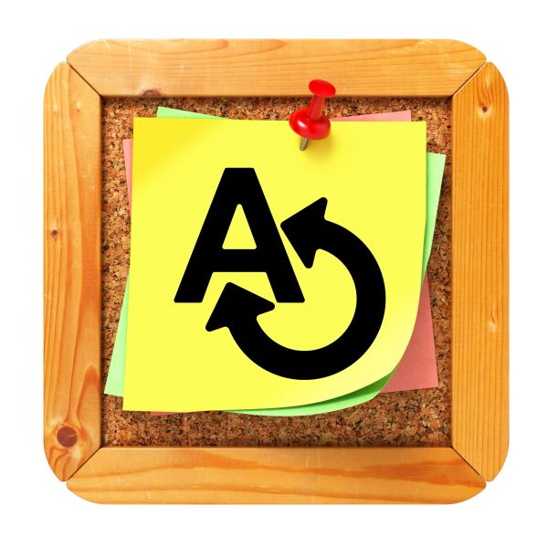 Sticky note with language translation symbol pinned on corkboard.