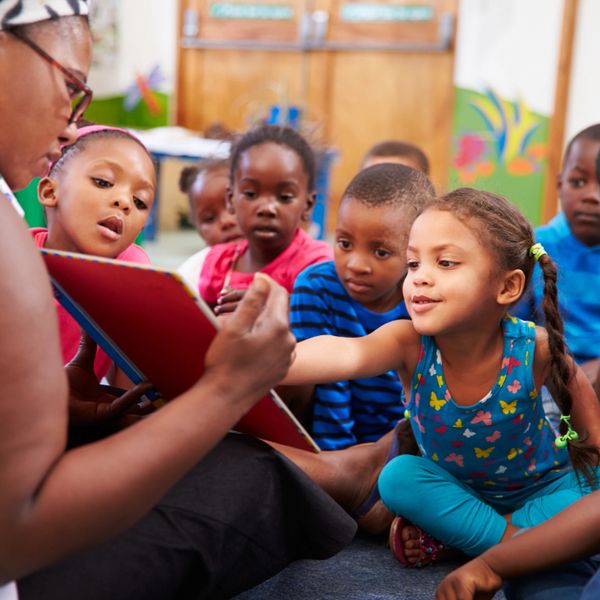 A teacher reading a book to a group of attentive young children.