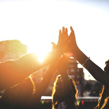 Group of people giving a high five with sunlight in the background.