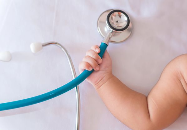 Baby holding a stethoscope on a white background.