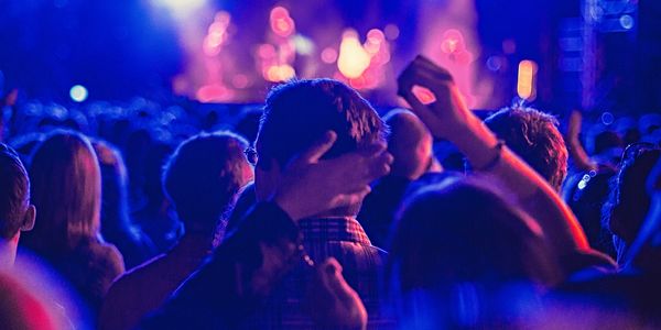 Crowd enjoying a live concert with vibrant blue and purple lighting.