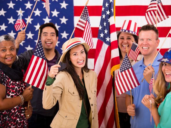 A diverse group of people waving American flags.