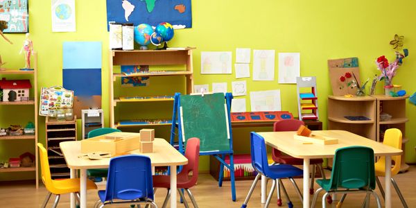 Colorful classroom with child-sized chairs, tables, and educational materials.