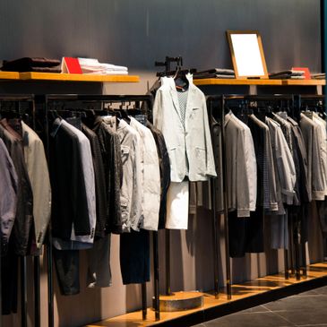 A row of men's jackets and shirts neatly hung in a stylish clothing store.