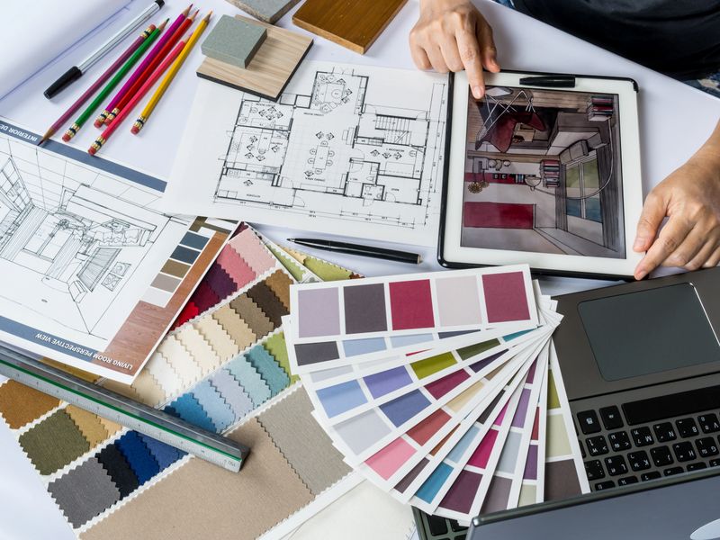 Top view of architects/ interior designer hands working with tablet computer, material sample on desk