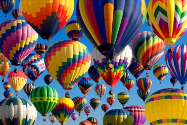 A picture of hot air balloons flying against a clear blue sky 