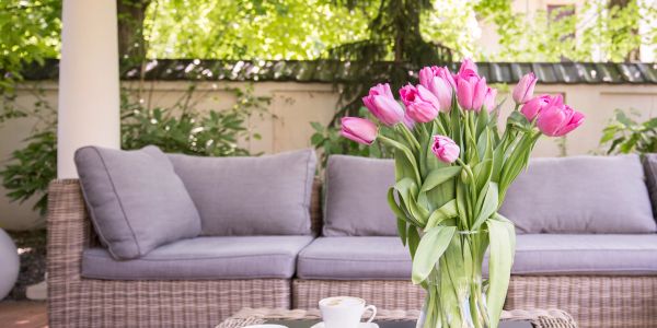 Pink tulips in a glass vase on a table outdoors.