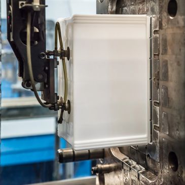 Close-up of a machine molding a white plastic container in a factory.
