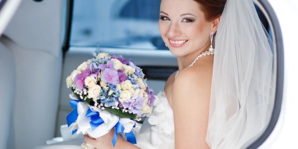 Smiling bride holding a colorful bouquet inside a car.