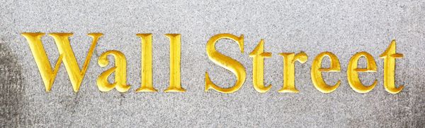 Golden Wall Street sign on stone background.