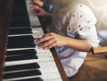Child playing piano, focusing on hands and keys.