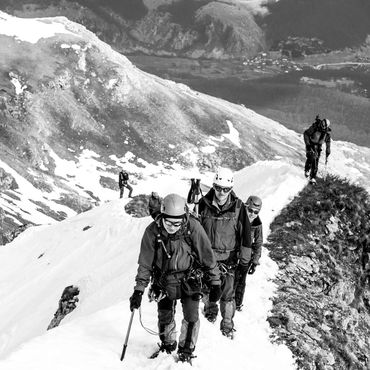 Group of climbers ascending a snowy mountain ridge.