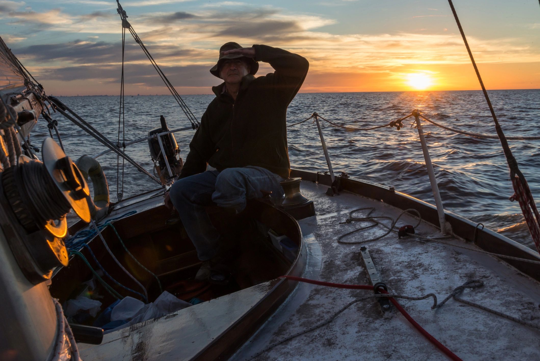 Sailor keeping watch aboard a yacht at sunset during practical sail training