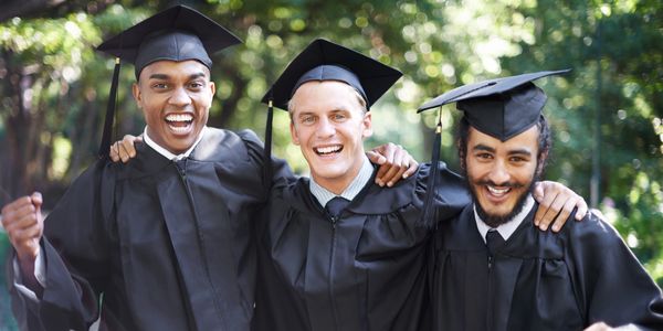 Three happy graduates in caps and gowns.