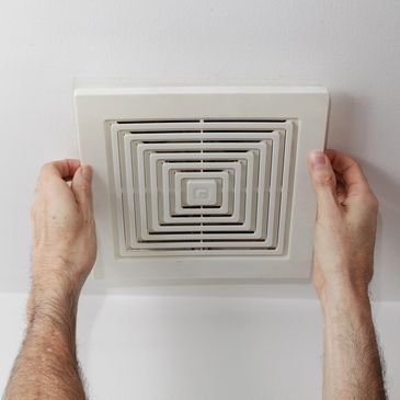 Hands holding a square ceiling vent.
