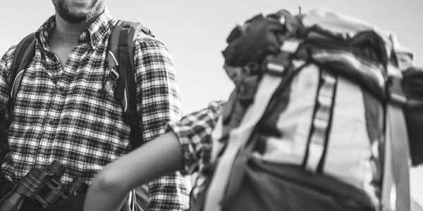 Two hikers with backpacks enjoying an outdoor adventure under a clear blue sky.