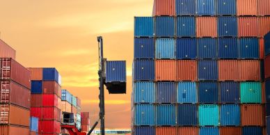 Containers being stacked at sunset in a shipping yard.