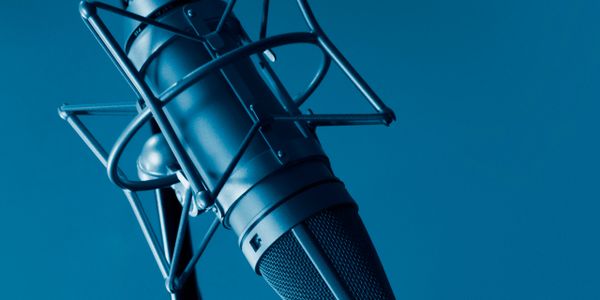 Close-up of a professional studio microphone with a blue tint.