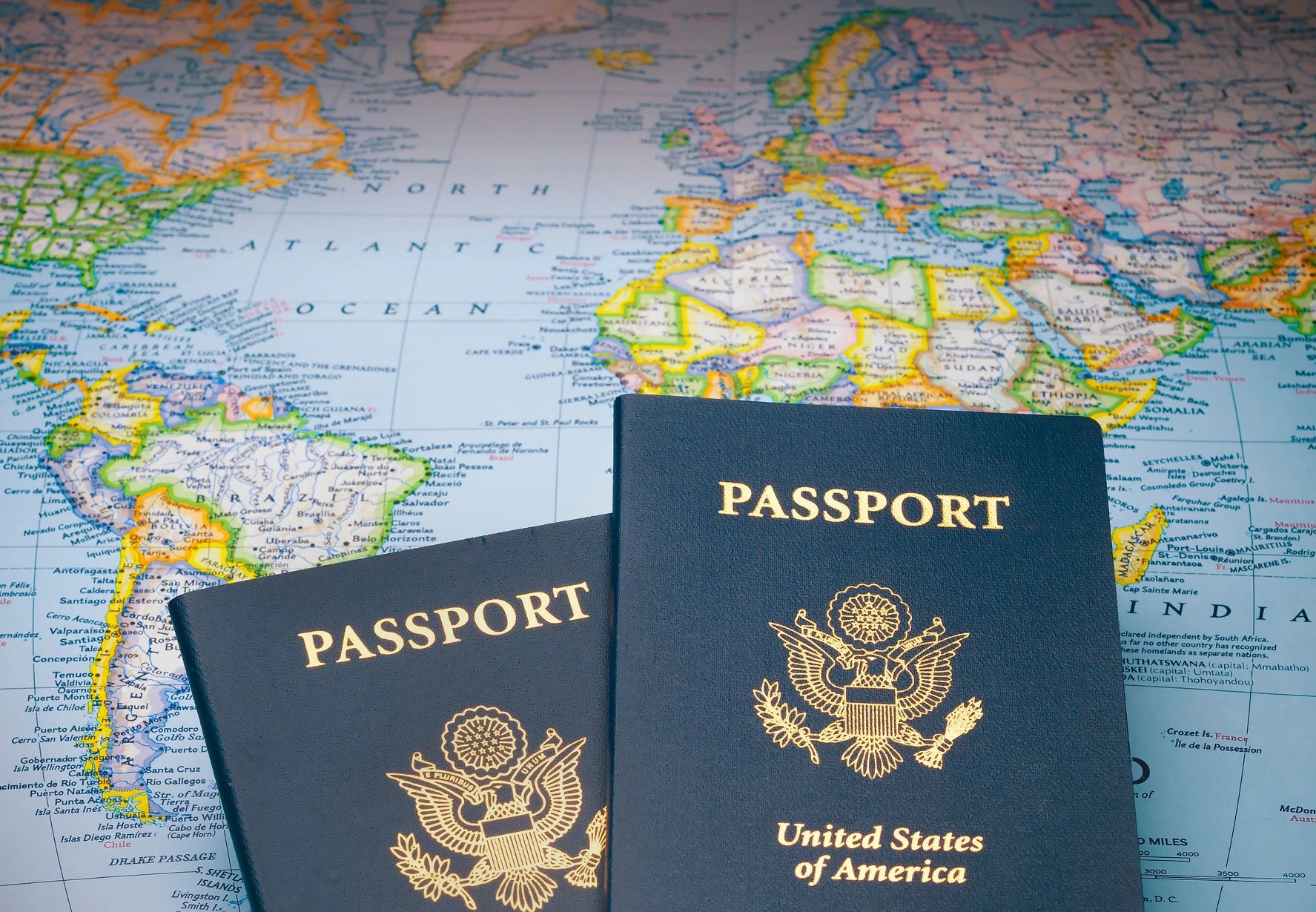 Two United States passports on a world map background.