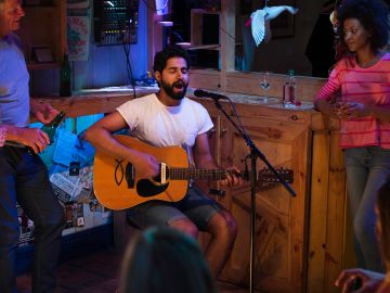 Man playing guitar and singing in a small bar.