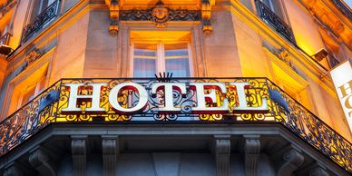 Illuminated hotel sign on a classic building balcony at dusk.