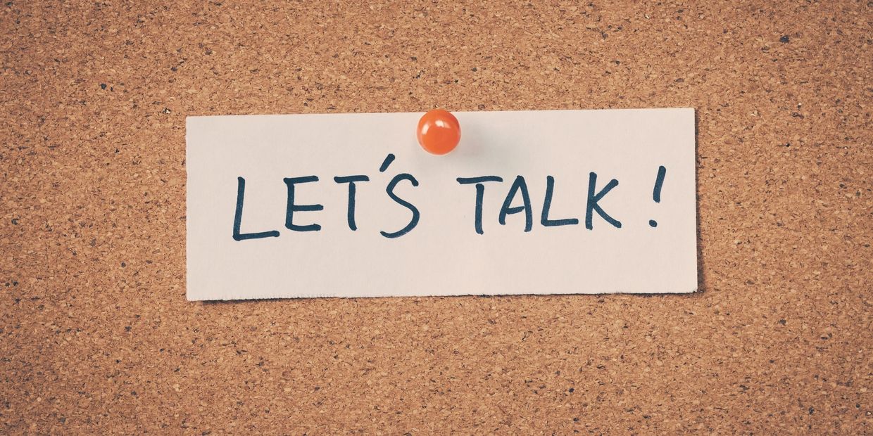 Note on corkboard reading 'LET'S TALK!' pinned with an orange thumbtack.