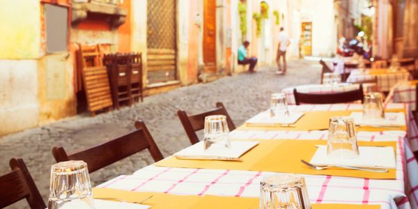 Outdoor tables set for dining on a cobblestone street in a charming town.