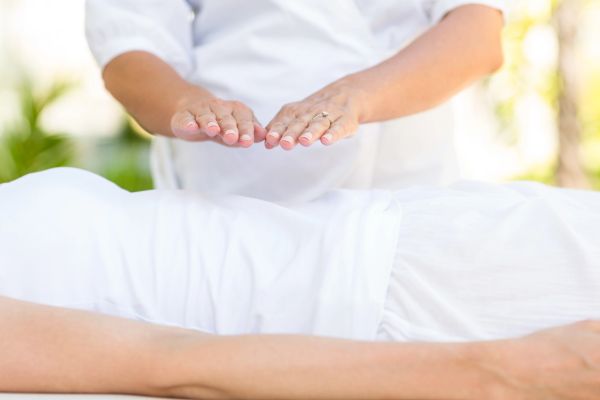 Therapist doing energy healing over patient.