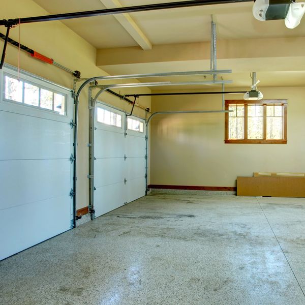Empty garage with two closed garage doors and a window