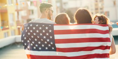 Family wrapped in an American flag outdoors.
