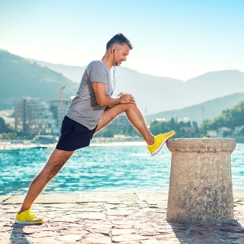 Man exercising and stretching legs on pier