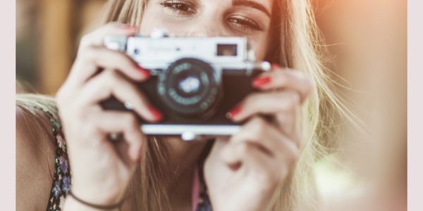Young woman holding a vintage camera, ready to take a photo.