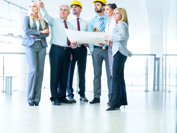 A diverse team of professionals reviewing architectural plans in a bright modern office.