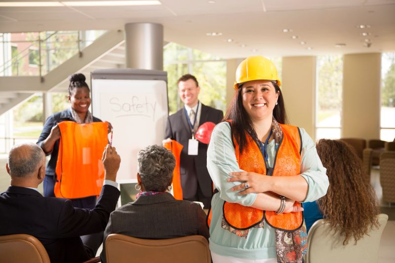 Business people give safety presentation at office. Multi-ethnic group of professionals. Latin construction worker in foreground.