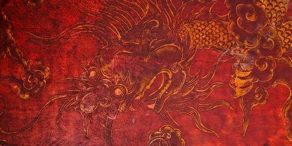 Ancient red and gold dragon mural with swirling clouds.