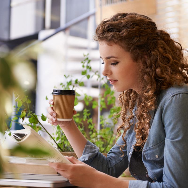 An attractive young woman drinking coffee while studying in a cafe