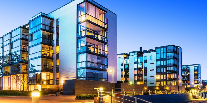 Modern waterfront apartment buildings illuminated at dusk.