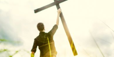 Person holding a large wooden cross.