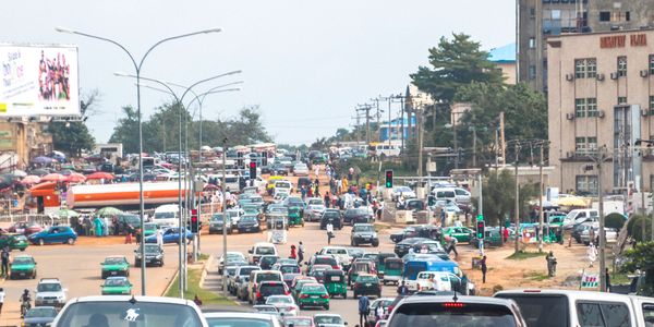 Busy city street filled with numerous cars and pedestrians under a clear sky.