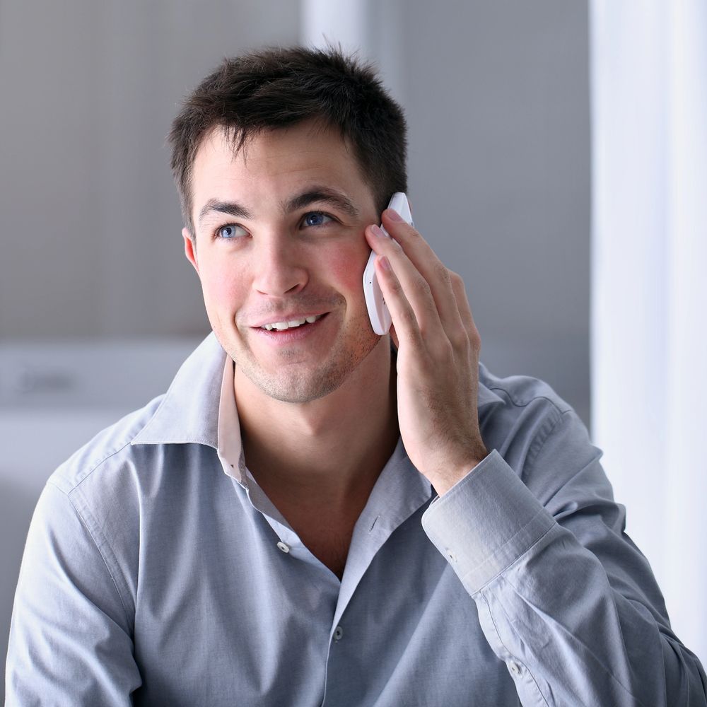 Smiling man talking on the phone indoors.