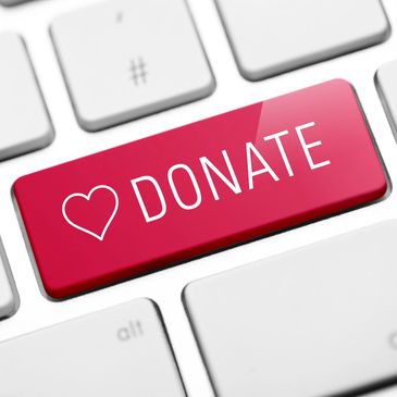 Red donate key on white keyboard with heart symbol.